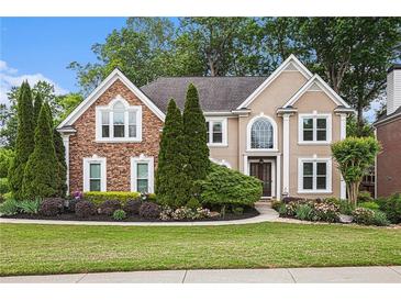 Charming two-story home featuring a well-manicured lawn and beautiful landscaping at 12350 Edenwilde Dr, Roswell, GA 30075
