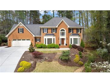 Charming two-story brick home featuring an attached two-car garage and lush landscaping with mature trees at 8920 Willowbrae Ln, Roswell, GA 30076