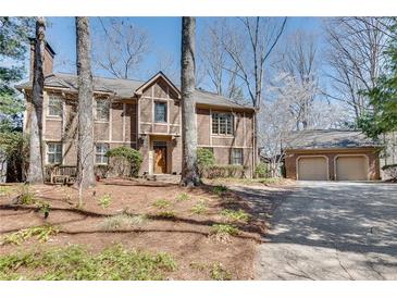 Traditional brick home with attached two-car garage and professionally landscaped front yard and mature trees at 24 Ball Creek Hl, Atlanta, GA 30350