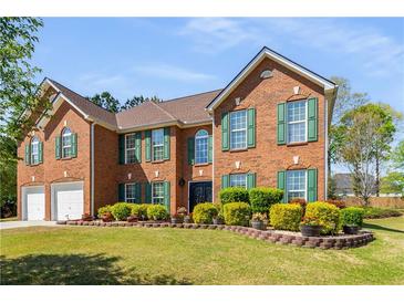 Beautiful brick home featuring a well-manicured lawn and traditional design with green shutters and multi-car garage at 308 Paper Woods Dr, Lawrenceville, GA 30046