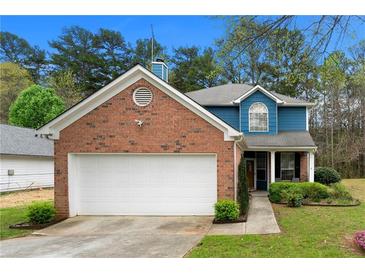 Charming two-story home with brick accents, a white garage door, and a well-manicured lawn at 2296 Raven Cir, Lithonia, GA 30058