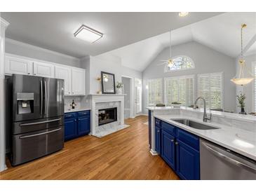 Modern kitchen featuring stainless steel appliances, a fireplace, and elegant white and blue cabinetry at 500 Meadowmeade Ln, Lawrenceville, GA 30043
