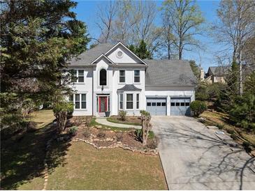 Charming two-story home features a well-manicured lawn, grey garage doors and a red front door at 6972 Sandtown Ln, Stone Mountain, GA 30087