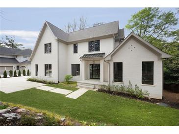 Charming two-story home featuring white brick, black-trimmed windows, manicured lawn, and concrete driveway at 1074 Moores Mill Nw Rd, Atlanta, GA 30327
