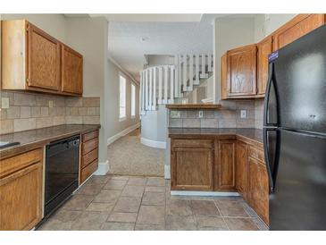 Traditional kitchen with oak cabinets and black appliances near a staircase with white railings at 1124 Lawton Sw Pl, Atlanta, GA 30310