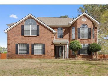 Charming two-story brick home featuring a well-manicured front lawn and traditional architectural details at 130 Arbor Cove Way, Stockbridge, GA 30281