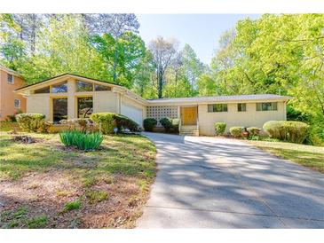 Charming single-story home with a brick facade, lush landscaping, and a long driveway at 558 Larchmont Nw Dr, Atlanta, GA 30318