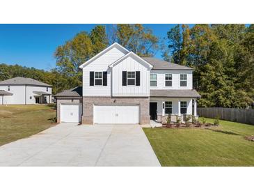 Charming two-story home featuring a brick and siding exterior with a spacious three car garage and well-maintained lawn at 2831 Centerville Rosebud Rd, Snellville, GA 30039