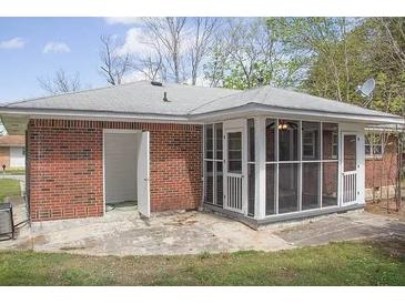 Exterior shot of brick home featuring a screened in porch and concrete patio at 130 Scarlet Dr, Jonesboro, GA 30236