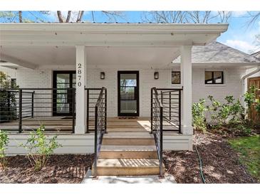 Inviting white brick home featuring a covered front porch with modern black railings and front door at 2870 Ridgemore Nw Rd, Atlanta, GA 30318