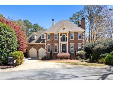 Stately brick home with mature landscaping and a two-car garage on a sunny day at 4620 Chattahoochee Se Xing, Marietta, GA 30067