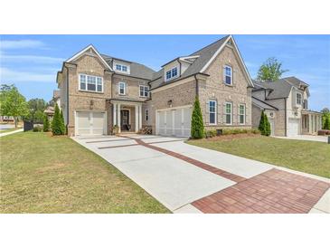 Beautiful brick home featuring a three-car garage, brick-lined driveway and manicured landscaping at 6210 Bellmoore Park Ln, Duluth, GA 30097