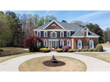 Stately brick home with manicured lawn, circular drive, and mature trees at 3230 Munsey Ct, Cumming, GA 30041