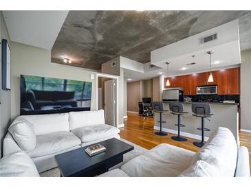 Bright living room with modern furnishings, open floor plan, and exposed concrete ceiling at 44 Peachtree Nw Pl # 629, Atlanta, GA 30309