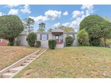 Charming one-story home featuring a well-manicured lawn, mature trees, and inviting front porch at 1679 Sw Lisbon Sw Dr, Atlanta, GA 30310