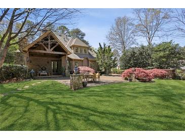 Expansive backyard featuring a stone patio with an outdoor dining area and a covered porch at 710 E Northway Ln, Atlanta, GA 30342