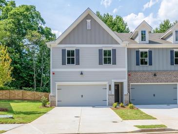 Charming townhome featuring a two-car garage, gray siding, and manicured lawn at 1628 Ruskin Way, Marietta, GA 30062