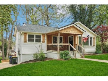 Charming home featuring a covered porch, lush lawn, fresh white siding, and detailed window trim at 353 Oak Ridge Se Dr, Marietta, GA 30060