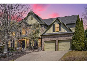 Beautiful brick home featuring an attached garage, mature trees, and manicured landscaping at dusk at 4030 Gold Mill Rdg, Canton, GA 30114