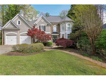 Charming two-story home featuring a three-car garage, stone accents, and lush landscaping at 2283 Edgemere Lake Cir, Marietta, GA 30062
