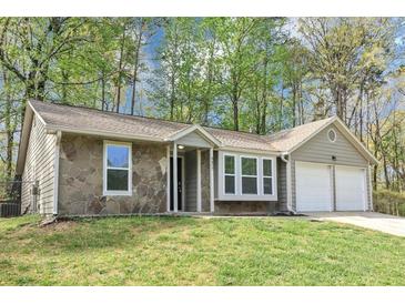 Charming single-story home with stone accents, a well-manicured lawn, and an attached two-car garage at 5477 Hedgeflower Ct, Stone Mountain, GA 30088