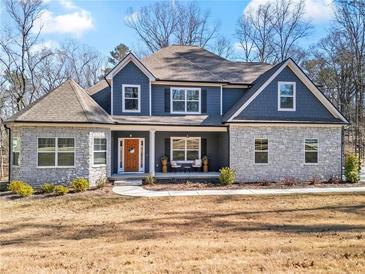 Charming two-story home featuring stone accents, blue siding, and a welcoming front porch with seating at 6710 Grayland Dr, Douglasville, GA 30135