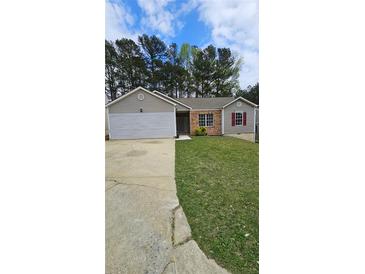 Charming single-story home with a well-maintained lawn, a combination brick and siding exterior, and an attached garage at 5760 Old Carriage Dr, Atlanta, GA 30349