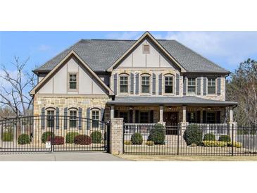 Stunning two-story home with a mix of stone and stucco, accented by black shutters and a gated entrance at 3308 Pate Rd, Snellville, GA 30078