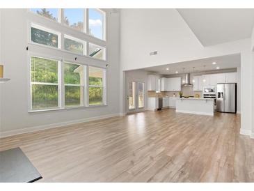 Open-concept living room featuring hardwood floors, large windows and an open view to the modern kitchen at 3681 Deaton Trl, Buford, GA 30519