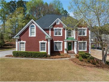 Charming red brick two-story home featuring a well-manicured lawn and mature trees at 2924 Meadow Church Rd, Suwanee, GA 30024