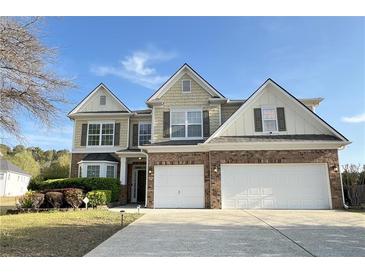 Inviting home featuring a well-manicured lawn, brick accents, and a two-car garage at 3354 Preserve Run Trl, Loganville, GA 30052