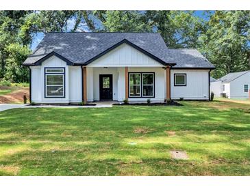 Charming single-story home featuring a well-manicured lawn and eye-catching modern farmhouse design at 2000 Grove Ave, East Point, GA 30344