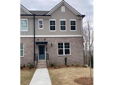 Charming townhouse featuring a brick facade, gray siding, and a well-manicured front lawn at 1250 Ainsworth Aly # 42, Sugar Hill, GA 30518