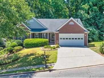 Charming brick home featuring a well-manicured lawn, mature trees, and a two-car garage at 1590 Highland Farm Dr, Suwanee, GA 30024