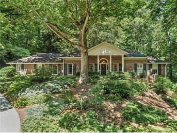 Charming brick home featuring mature trees and lush landscaping create a serene and private setting at 4590 Lake Forrest Nw Dr, Atlanta, GA 30342