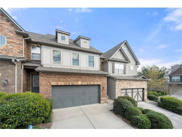 Two-story brick and stone townhome with gray garage doors and manicured landscaping at 5649 Cobblestone Creek Pl # 13, Mableton, GA 30126