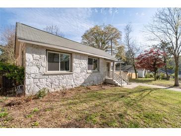Charming stone home featuring mature trees and a well-maintained lawn on a sunny day at 1441 Ezra Church Nw Dr, Atlanta, GA 30314