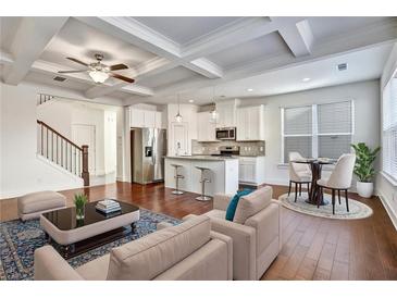 Bright, open-concept living room showcasing modern kitchen, coffered ceilings, and elegant hardwood floors at 2240 Mulsanne Dr, Lithonia, GA 30058