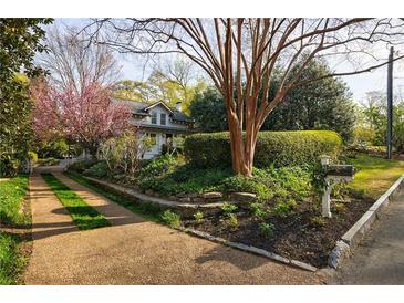 Charming home featuring a meticulously landscaped front yard with flowering trees and lush greenery at 202 Lakeview Ave, Atlanta, GA 30305