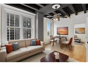 Modern living room featuring hardwood floors, large windows, and a comfortable sofa with decorative pillows at 32 Peachtree Nw St # 1303, Atlanta, GA 30303