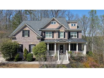 Charming two-story brick home featuring a welcoming front porch and manicured landscaping, surrounded by mature trees at 4514 Heathrow Nw Ct, Kennesaw, GA 30152