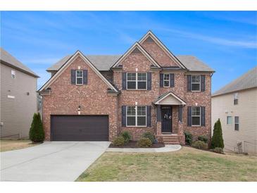 Beautiful brick home with a well-manicured lawn and attached two-car garage under a clear blue sky at 4604 Marching Ln, Fairburn, GA 30213