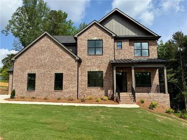 Beautiful brick two-story home with black trim windows, a covered porch, and lush green lawn at 6120 Hutchins Dr, Buford, GA 30518
