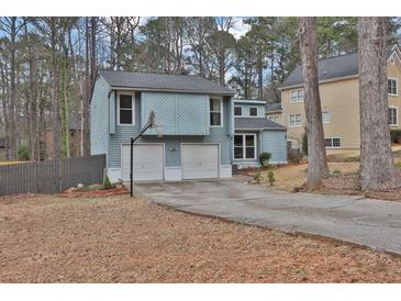 Charming light blue home features a two-car garage and basketball hoop in a wooded suburban neighborhood at 670 Westbrook Pl, Lawrenceville, GA 30044