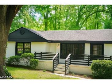 Charming single-story home featuring white stucco and black trim in a lush, green setting at 1956 Shirley Sw St, Atlanta, GA 30311