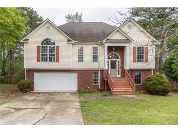 Traditional two-story home with a two-car garage, red shutters, and landscaped front yard at 703 Paul Revere Dr, Locust Grove, GA 30248