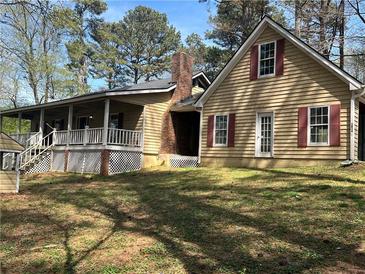 Charming home with a welcoming porch, brick chimney, and red shutters nestled among mature trees at 5834 Heardsville Rd, Cumming, GA 30028