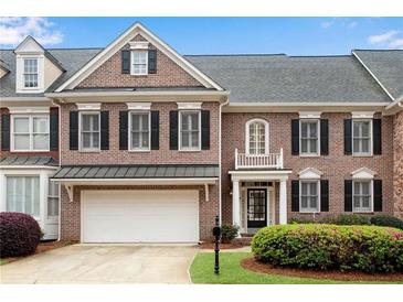 Charming brick townhome featuring an attached garage, black shutters, and manicured landscaping in a desirable community at 611 Vinings Estates Se Dr, Smyrna, GA 30126