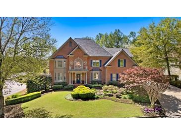 Beautiful two-story brick home with a manicured front lawn and mature trees in a desirable neighborhood at 9985 High Falls Pointe, Johns Creek, GA 30022