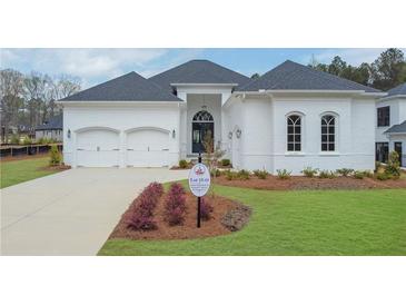 Beautiful white brick home with a manicured lawn, arched windows, a two-car garage and a dark, arched front door at 103 Candler Loop, Acworth, GA 30101